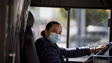 a friendly bus driver wearing a mask. 